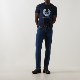 Model wearing Belstaff Dark Ink crew neck T-shirt with phoenix graphic, styled with dark wash jeans and a brown belt.