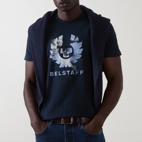 Model wearing Belstaff Crew Neck T in Dark Ink with large logo graphic print, styled with jeans and a navy hoodie draped over shoulders.