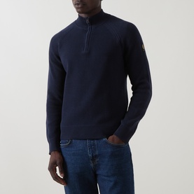 Model wearing Belstaff Half Zip in Dark Ink, 100% cotton knit with quarter zip neck and logo badge on sleeve, styled with blue jeans.
