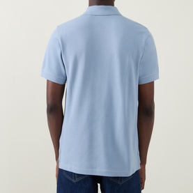 Model wearing Belstaff Phoenix Logo Polo Shirt in Mist Blue, rear view, styled with dark blue jeans.
