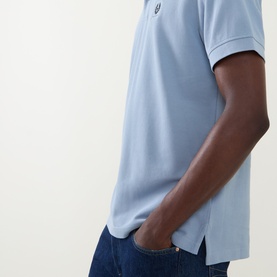 Model wearing Belstaff Phoenix Logo Polo Shirt in Mist Blue with tonal Phoenix badge, styled with dark blue jeans.