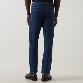 Model wearing Belstaff 3049 Straight Jeans in washed indigo, rear view, with dark leather shoes.