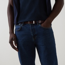 Model wearing Belstaff 3049 Straight Jeans in Washed Indigo, styled with a brown leather belt and navy T-shirt.