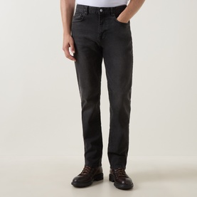 Model wearing Belstaff B69 Straight-Leg Jeans in Washed Black, styled with brown leather boots, showing straight-leg cut and five-pocket styling.