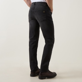 Model wearing Belstaff B69 Straight-Leg Jeans in Washed Black, shown from behind, paired with dark brown leather shoes.