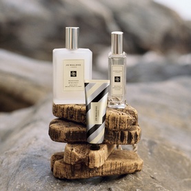 Jo Malone bath and body gift set displayed on layered driftwood rocks, featuring a body lotion, cologne and hand cream