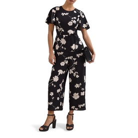 Model wearing Phase Eight black ivory floral print jumpsuit with flutter sleeves and wide-leg cropped trousers, styled with black heels and clutch