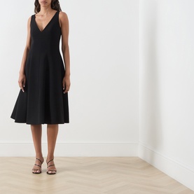 Model wearing Max Mara Studio black sleeveless V-neck midi dress with flared skirt, styled with gold strappy heeled sandals.