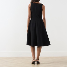Model wearing Max Mara Studio black sleeveless midi dress, back view, with full A-line skirt and bateau neckline, styled with black heeled mules.