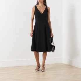 Model wearing Max Mara Studio black V-neck sleeveless fit-and-flare midi dress, styled with strappy sandals and a small black handbag.