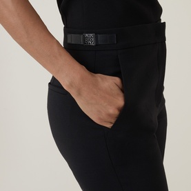 Model wearing Max Mara Main Acino Straight-Leg Trousers in black with leather trim hardware detailing and side pocket visible.