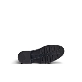 Black rubber lug sole of a shoe, showing treaded outsole pattern with ribbed grip and slight heel, viewed from below.