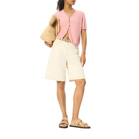 Model wearing Whistles pink short-sleeve cardigan with cream wide-leg shorts and tan strappy sandals, carrying a shearling bag.