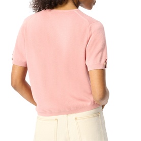 Model wearing Whistles pink short-sleeve knit top, back view, with button-tab sleeve detail, styled with cream trousers.