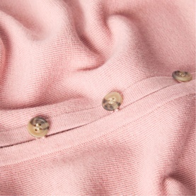 Whistles pink knit fabric close-up showing decorative gold-tone buttons on a fine-knit seam detail.