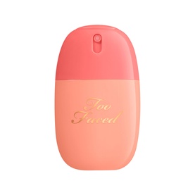 Too Faced Peach Mist Setting Spray in a peach-pink bottle with gold script branding and fine-mist nozzle