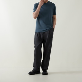 Model wearing Belstaff Alloy Logo T-Shirt in petrol, styled with dark charcoal trousers and black loafers