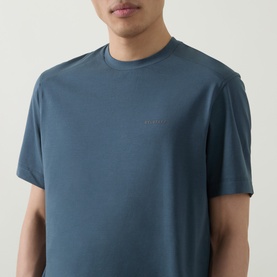 Model wearing Belstaff Alloy Logo T-Shirt in petrol blue, featuring a crew neck, short sleeves, and subtle chest logo detail.