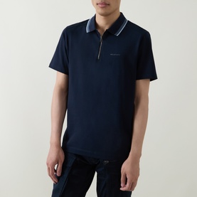 Model wearing Belstaff Alloy Logo Tipped Zip Polo Shirt in Dark Ink, with tipped collar, zip neckline and short sleeves.
