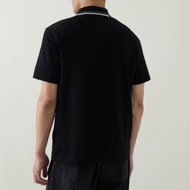 Model wearing Belstaff Alloy Logo Tipped Zip Polo Shirt in black, showing rear view with white tipped collar detail and short sleeves