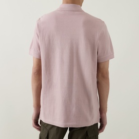 Model wearing Belstaff Logo Badge Polo Shirt in Dusk Pink, rear view, with khaki trousers. Short sleeves, polo collar, cotton piqu&eacute; fabric.