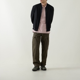 Model wearing Belstaff Logo Badge Polo Shirt in Dusk Pink, styled with dark bomber jacket, olive cargo trousers and grey shoes.