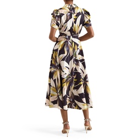 Model wearing Phase Eight black multi tropical leaf print midi dress with puff sleeves and wrap silhouette, styled with gold heeled sandals
