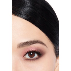 Close-up of model's eye wearing rosy-pink shimmer eyeshadow with defined brows and subtle lower lash line highlight