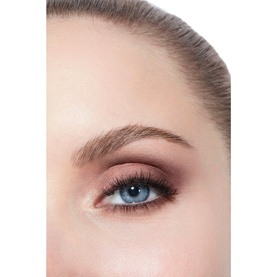 Close-up of model's eye wearing warm burgundy and brown smoky eyeshadow with defined lashes and groomed brows