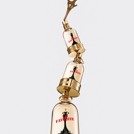 Jean Paul Gaultier La Favorite Eau de Parfum stacked triple bottle display in gold with red logo lettering, festive cracker-style design