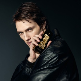 Model with Paco Rabanne 1 Million Black Eau de Parfum held to face, wearing black leather jacket, dark background