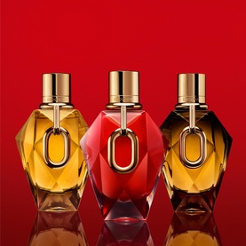 Paco Rabanne Million Red For Her Parfum shown alongside two complementary fragrances in amber bottles, all with gold oval hardware, red background