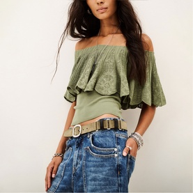 Model wearing Bash green off-shoulder bardot frill top, styled with blue jeans and a tan belt