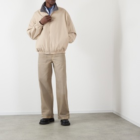 Model wearing Acne Reversible Logo Jacket in beige with matching beige trousers and black loafers.