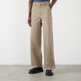Model wearing Acne Stained Twill Trousers in camel beige, wide-leg fit with upturned hems, styled with black chunky sole shoes.