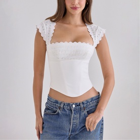 Model wearing House of CB white lace cap sleeve corset top, styled with light wash denim jeans