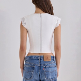 Model wearing House of CB white crop top with lace trim sleeves, zip back detail, styled with blue denim jeans. Rear view.