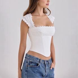 Model wearing House of CB white square-neck crop top with lace cap sleeves, styled with light wash denim jeans
