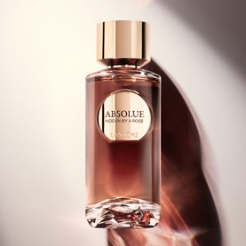 Lanc&ocirc;me Hidden By A Rose Eau De Parfum in amber glass bottle with gold cap, crystal-faceted base, soft warm-toned background