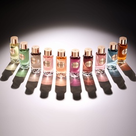 Lanc&ocirc;me Hidden By A Rose Eau De Parfum displayed in a collection of nine varied-hue bottles with gold caps arranged in a semicircle