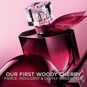 Lanc&ocirc;me woody cherry EDP in deep burgundy bottle with crystal stopper and red bow, promotional shot with fragrance descriptor text