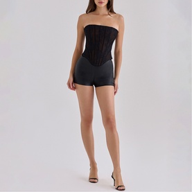 Model wearing House of CB black strapless corset top with matching black shorts and strappy heeled sandals