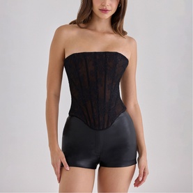 Model wearing House of CB black lace strapless corset top, styled with black faux leather mini shorts