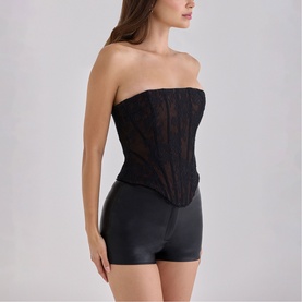 Model wearing House of CB black lace strapless corset top styled with black shorts