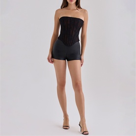 Model wearing House of CB black strapless boned corset top and black mini shorts, styled with strappy heeled sandals