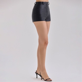Model wearing House of CB black faux leather high-waist shorts, styled with sheer tights and strappy heeled mules