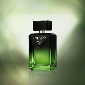 Prada Parfum in a square green glass bottle with black cap and triangular logo, on a soft green background