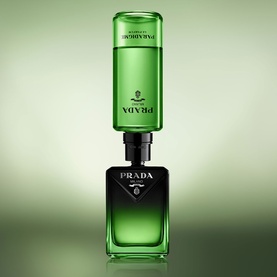 Prada Parfum in green glass bottle with refillable black base and green refill cartridge stacked on top, against green background.