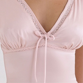 Model wearing House of CB pink top with lace trim neckline, bow tie detail, and short sleeves. Close-up chest shot.
