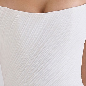 Model wearing House of CB white textured sleeveless top with diagonal pleated detail, close-up shot showing neckline and fabric texture.